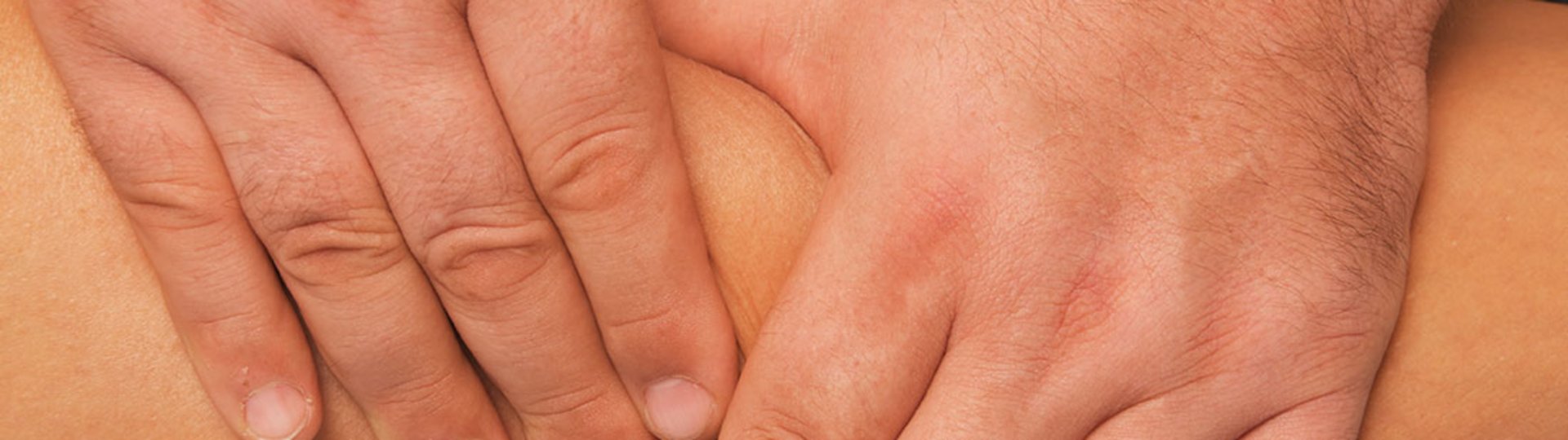 Zwei männliche Hände massieren ein Bein