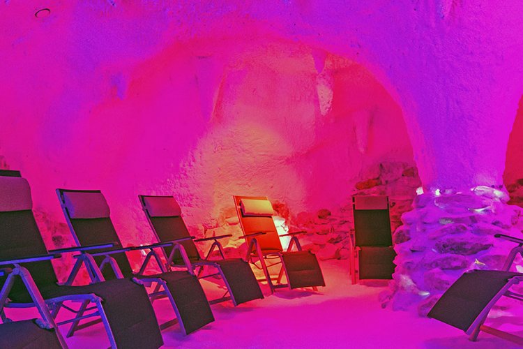 Leere Liegestühle stehen in einer pink angeleuchteten Grotte