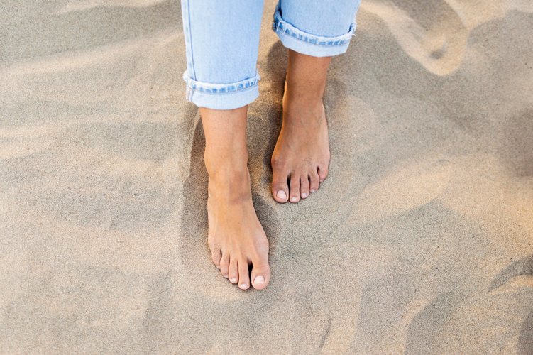 Zwei nackte Füße stehen im Strandsand