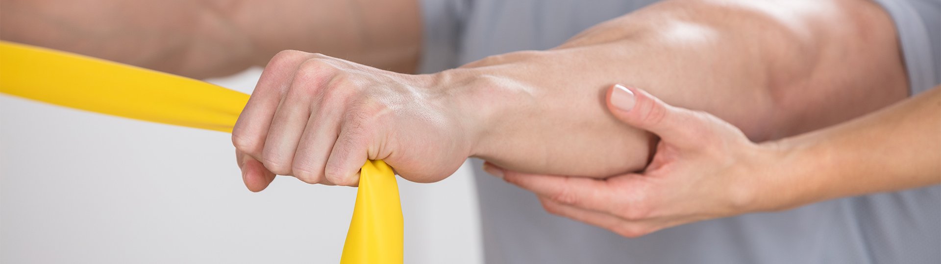 Eine männliche Hand hält ein gelbes Teraband und wird von einer weiblichen Hand dabei geführt