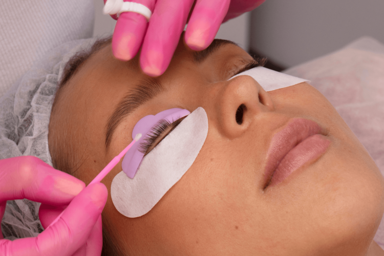 Behandschuhte Hände bearbeiten die Wimpern einer jungen Frau