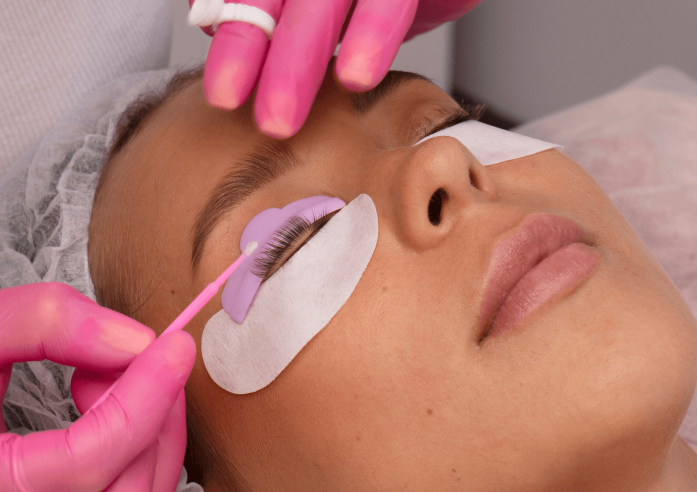 Behandschuhte Hände bearbeiten die Wimpern einer jungen Frau