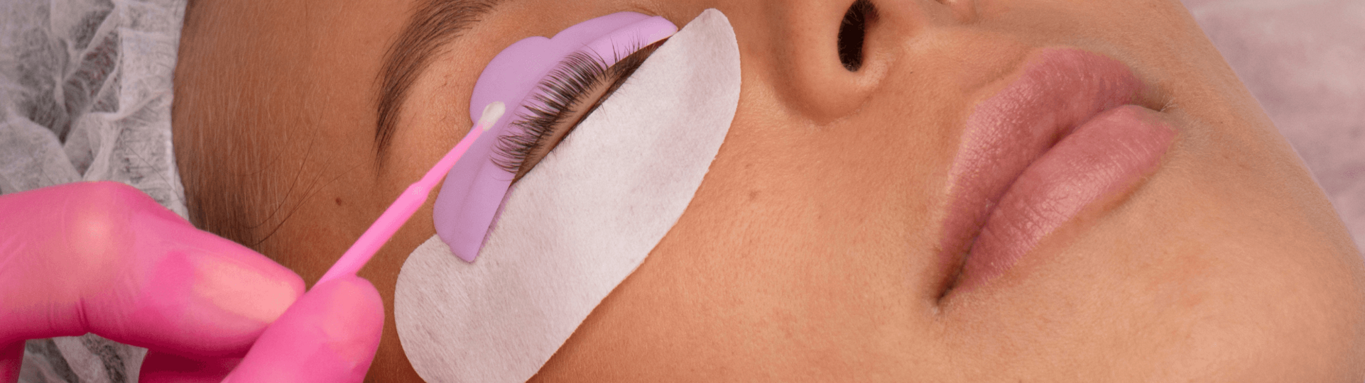Behandschuhte Hände bearbeiten die Wimpern einer jungen Frau
