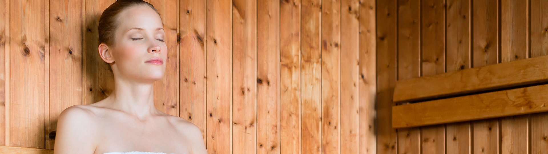Eine Frau sitzt mit geschlossenen Augen in einer Sauna