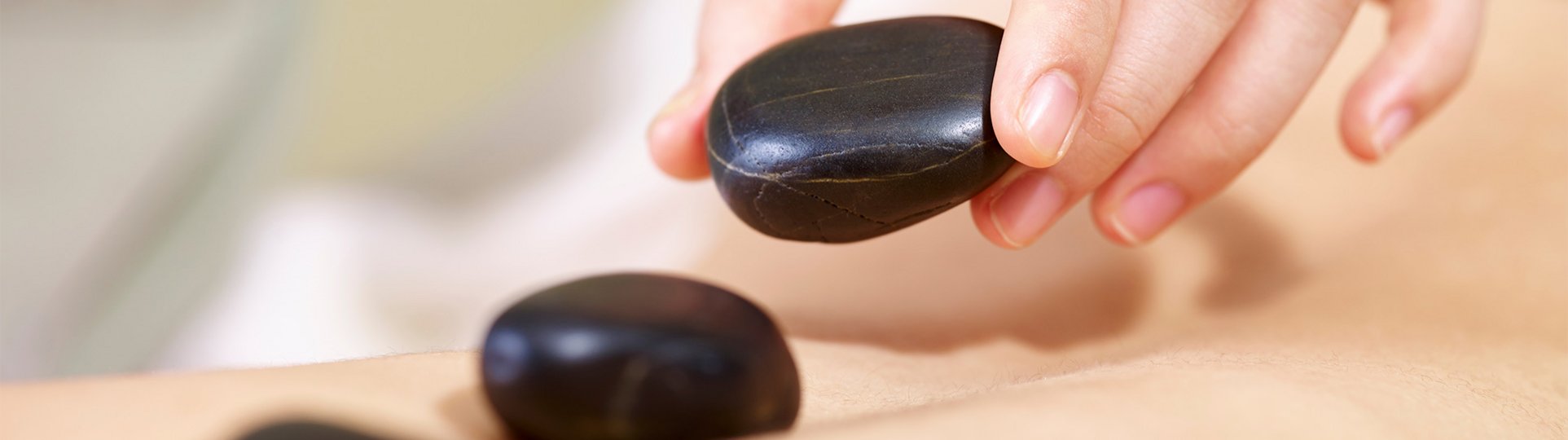 Ein weibliche Hand legt schwarze Steine auf einen Rücken