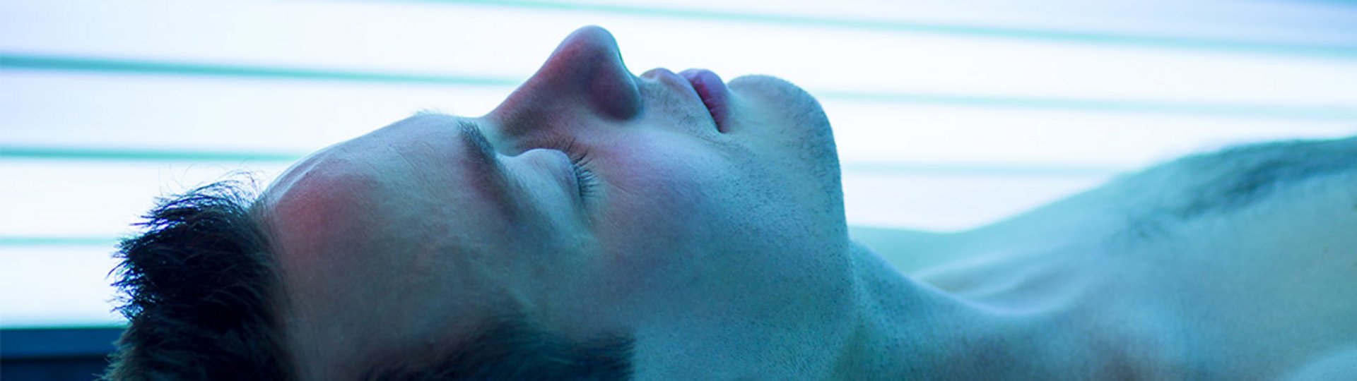 Ein junger Mann liegt in einem blau beleuchteten Solarium